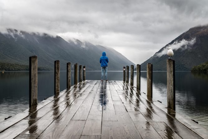 Person standing in brown wooden dock in Lake Rotoiti, o a solo tip to New Zealand